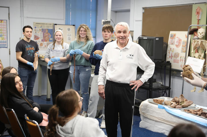 don frazier standing and smiling while showing high school students scientific specimens