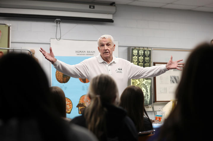 don frazier standing in front of a class of students lecturing with his arms wide open