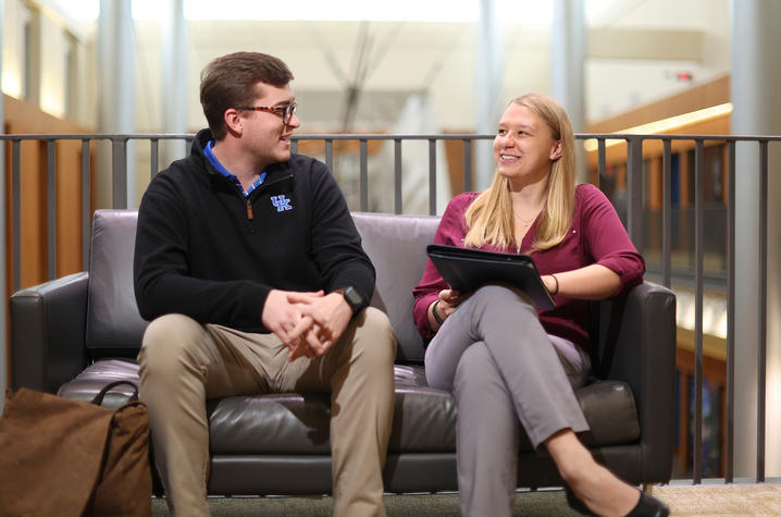 Two people sitting on couch talking. 