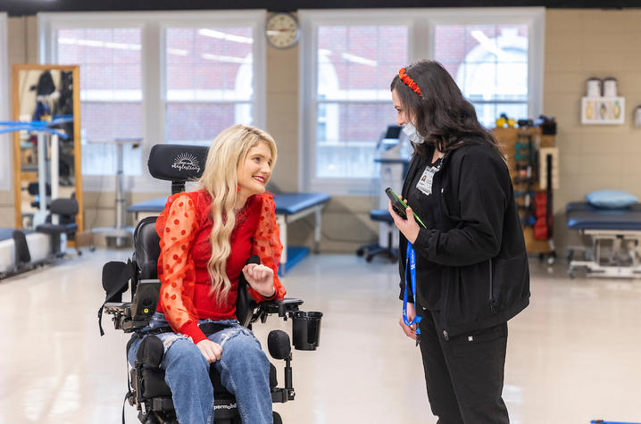 kayla sitting, talking to a physical therapist