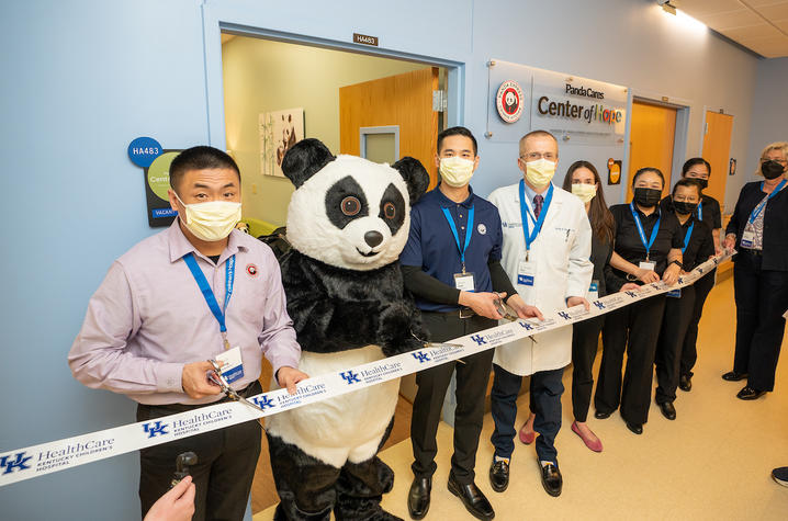 Image of Panda Express staff and costumed Panda mascot with KCH leadership cutting a ribbon outside the new quiet space