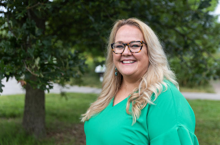 Image of Lori Wilson in green dress standing outside by a tree