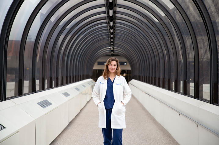 image of Dr. London-Bounds in scrubs with white coat standing in long cooridor.