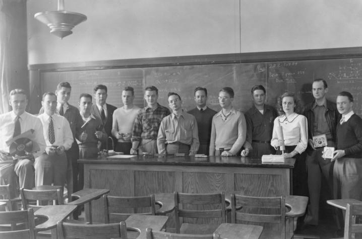 black and white photo of students in a circa 1940 classroom holding item representing area of study