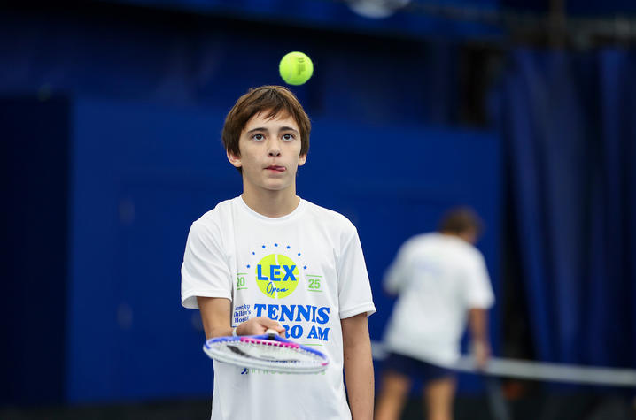 Image of young man bouncing a tennis ball on a tennis racket