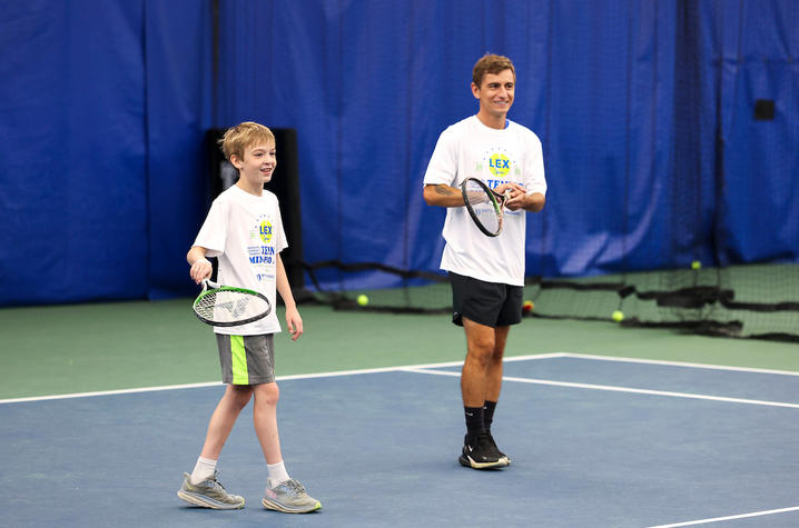 Image of young man and young boy on a tennis court