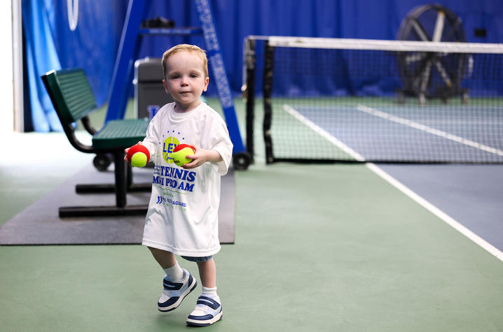 Image of little boy holding two tennis balls