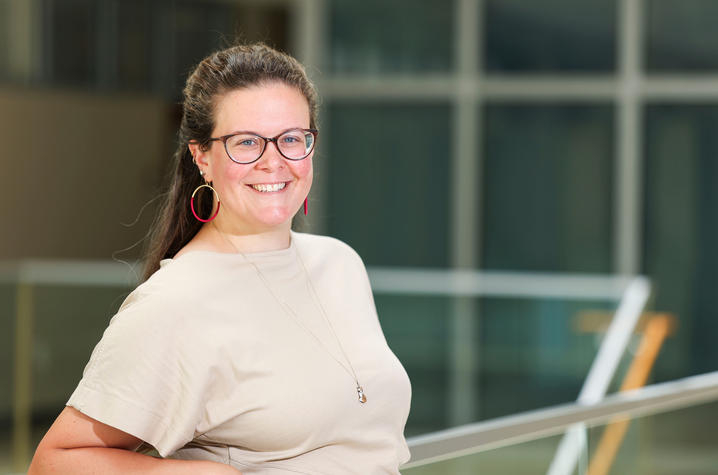 Caroline Geisler leans back on a glass ledge and smiles for a portrait