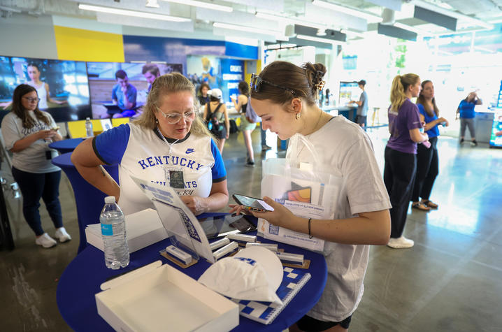  A student receives assistance from a staff member at a campus welcome table while picking up technology and orientation materials during a student support event.
