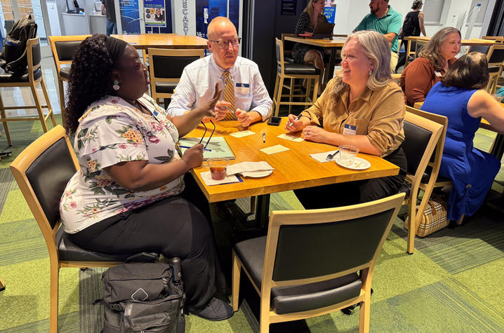 Three people — a Black woman, white man, and white woman, seated at a table. 
