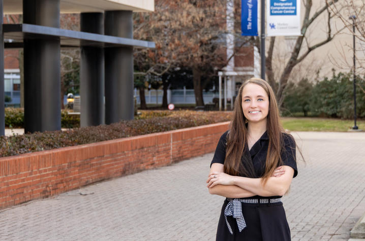 Gabby Morrison A young woman in professional attire smiles confidently on a university campus with brick pathways and modern buildings.