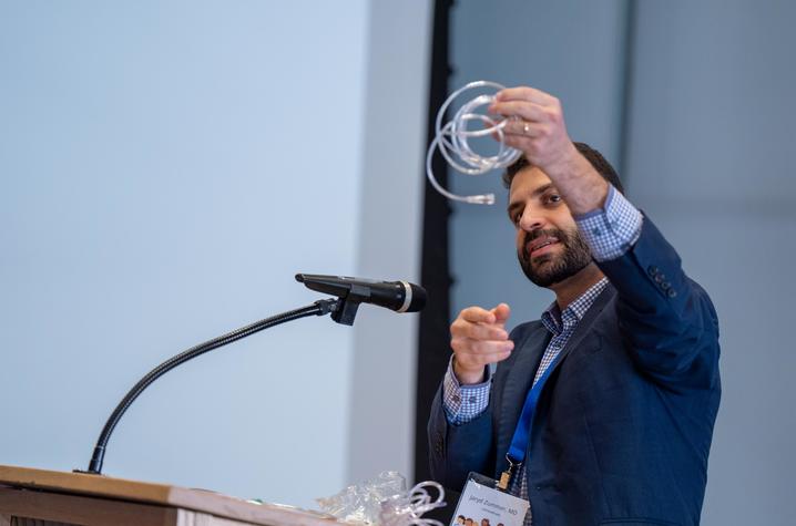 Image of physician holding up a plastic tube during presentation
