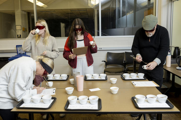 photo of Tasting exercise at UK’s Coffee Lab roastery Four blindfolded participants evaluate samples on trays in a classroom setting.