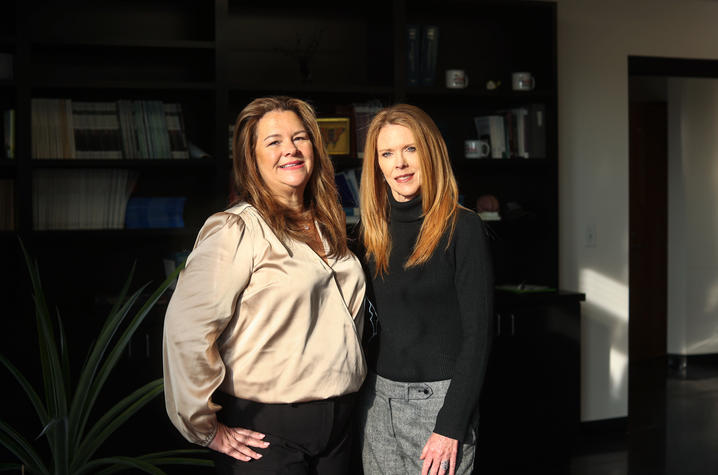 Two people standing together in a modern office with bookshelves in the background.