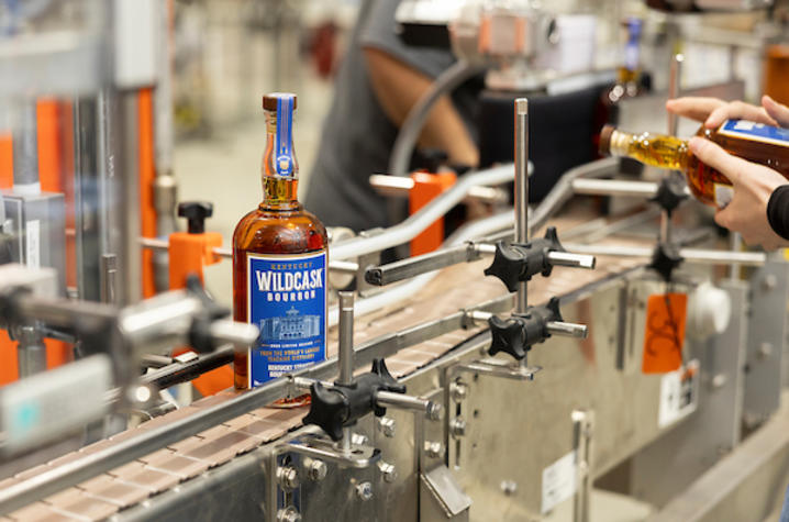 A bottle of Wildcask Bourbon on the steel machine within the bottling line
