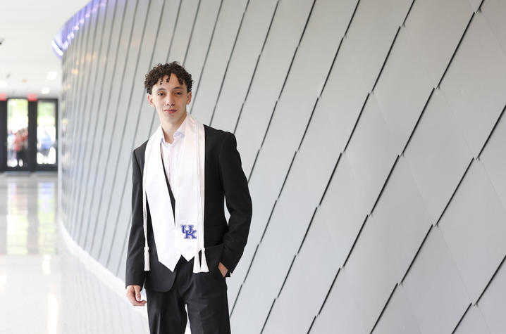 photo of Mostafa Mubarak A student stands in a modern campus building hallway, next to a curved wall with geometric paneling.