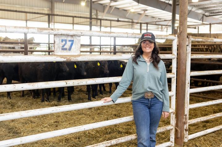 Photo of student at Bluegrass Stockyards Person poses for a portrait in front of cattle at Bluegrass Stockyards.