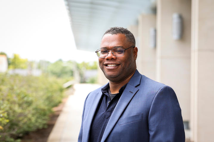 A person smiles for a portrait outside a research building.