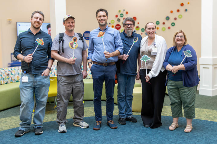 UK gamified walking test team Members of a project team stand together in a pediatric clinic and hold colorful space-themed game wands.
