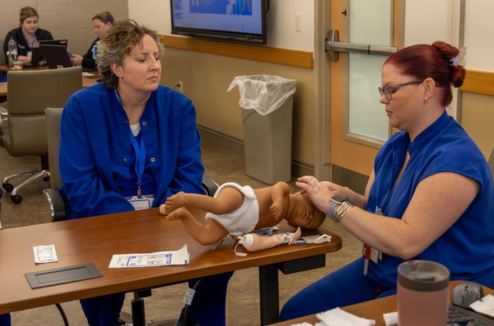 photo of providers recieving training at golisano affiliate network conference Two conference attendees practice infant care skills with a training mannequin during a hands-on pediatric simulation session.