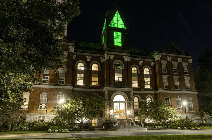 UK goes green Historic red-brick academic building illuminated at night, with a glass cupola glowing bright green above the roofline.