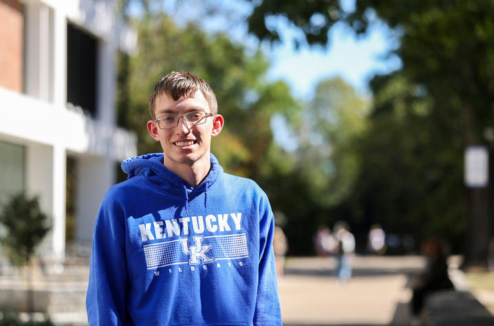 Person wearing a blue Kentucky Wildcats hoodie stands outdoors on the University of Kentucky campus.