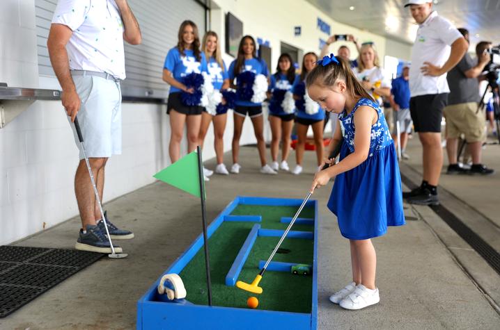 Image of young girl in blue dress putting on mini golf course