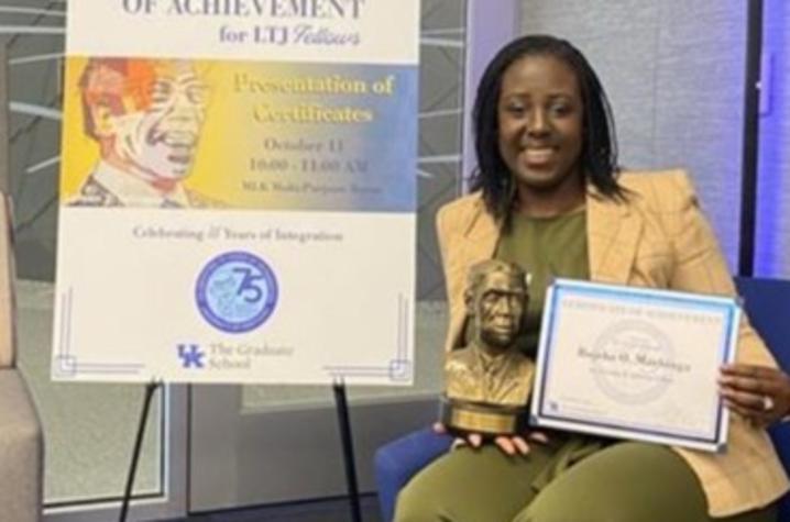 Fellowship awardee poses with Lyman T. Johnson bust 