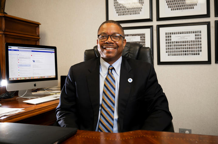 Dean Brennen sits behind desk in suit