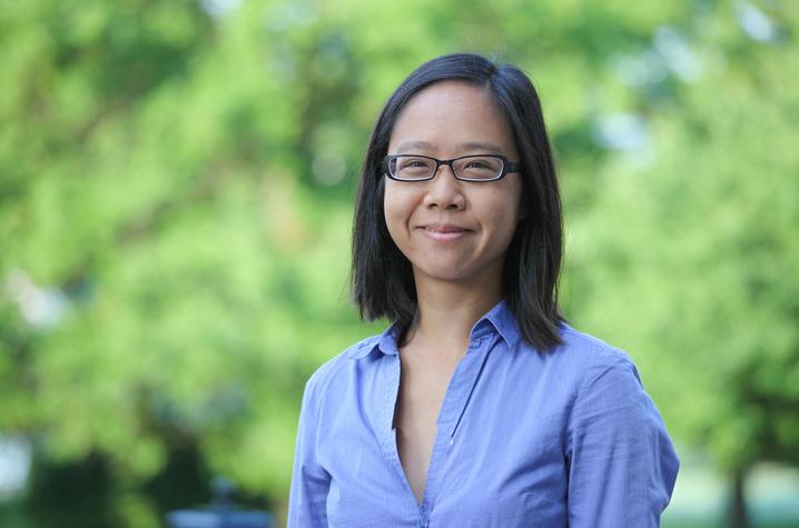 Woman with black hair, wearing eyeglasses and a blue shirt