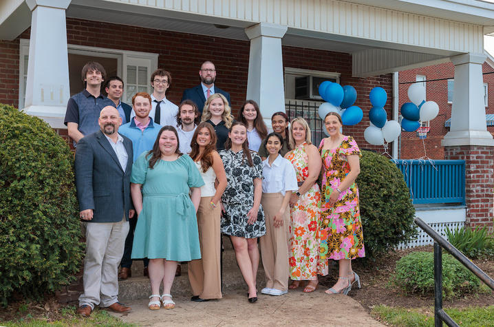 photo of Community Innovation Lab group A group of people pose outside a brick building entrance decorated with blue and white balloons.