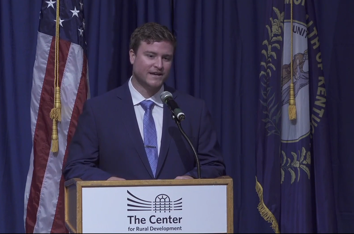 Photo of Colby Hall at a podium that says The Center for Rural Development with the US and Kentucky flags behind him