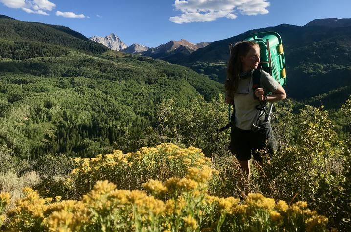 photo of Brittney Woodrum climbing mountain in Colorado standing in flowers