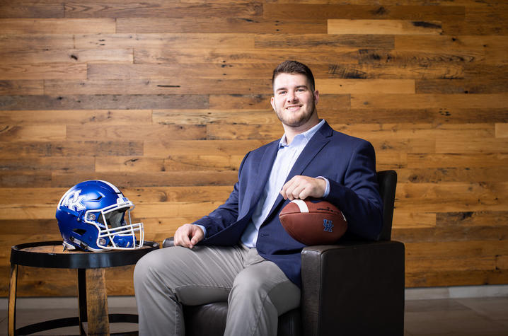 eli cox sitting and smiling with a football