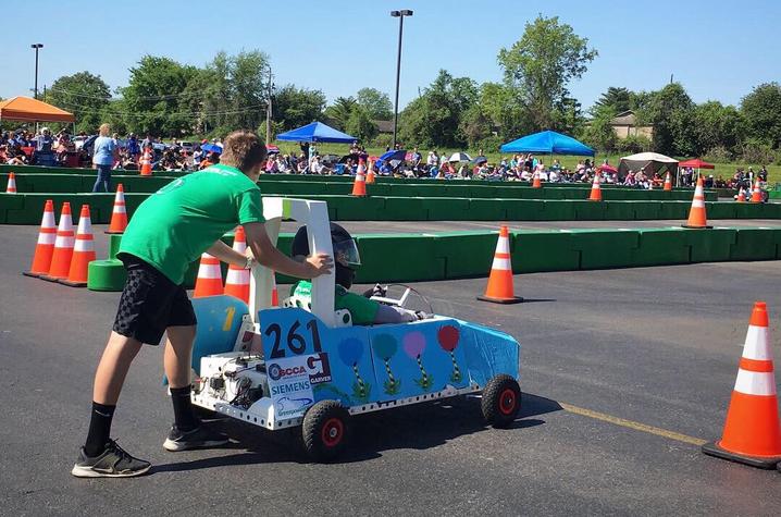 photo of young student pushing electric vehicle at race track
