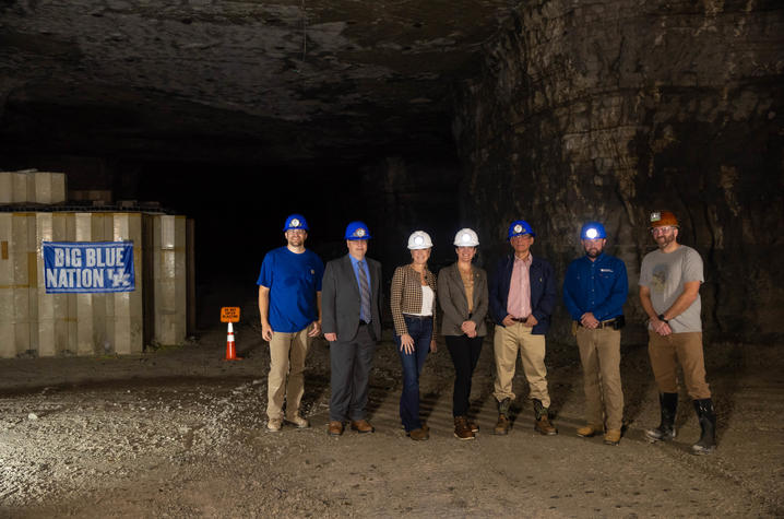 Group wearing hard hats poses inside an underground mine. Group wearing hard hats poses inside an underground mine.