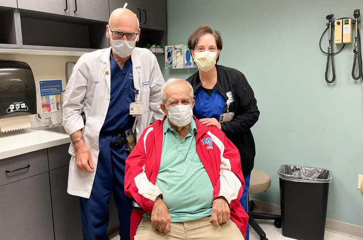 a patient, doctor, and nurse standing in an exam room.