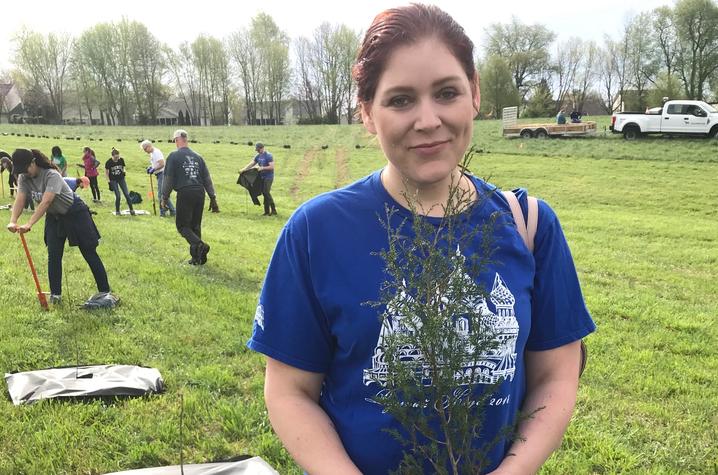 photo of Elizabeth Avery holding small tree at planting event