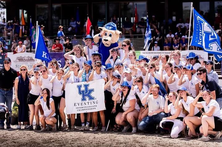 Kentucky Eventing Team members posing for a photo A large group of University of Kentucky Eventing team members and supporters gathers for a group photo at an outdoor equestrian competition venue.