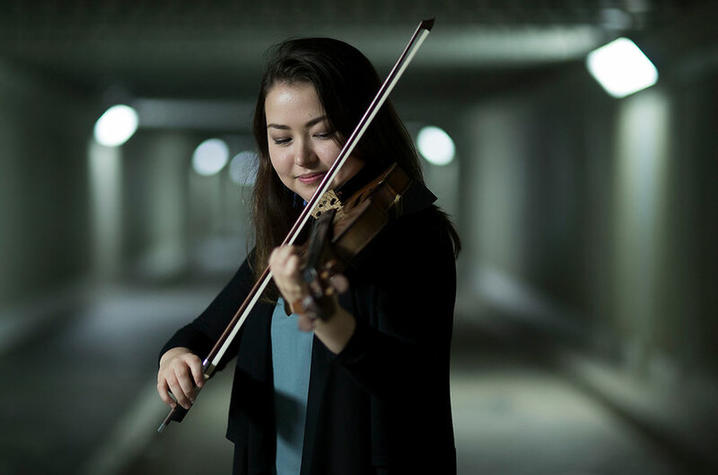 Salina Fisher in underground hall/tunnel playing violin