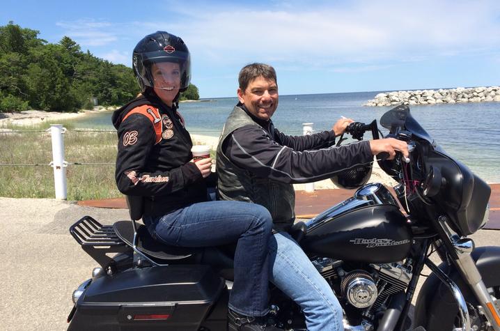 This is a photo of Carl Mattacola and his wife, Kathleen, riding a motorcycle.  