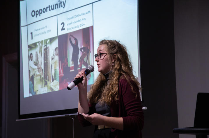 White female holding a microphone giving a presentation