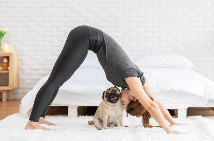 photo of woman doing yoga and kissing her dog who is smiling