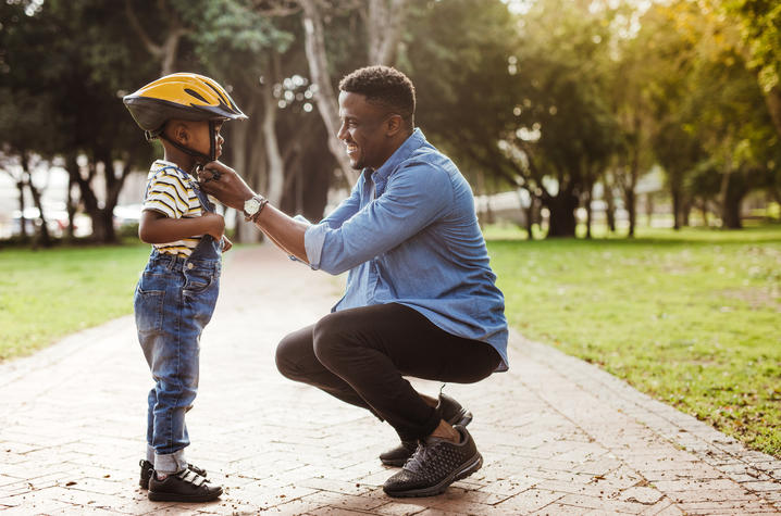 image of father putting a bike helmet on his son.