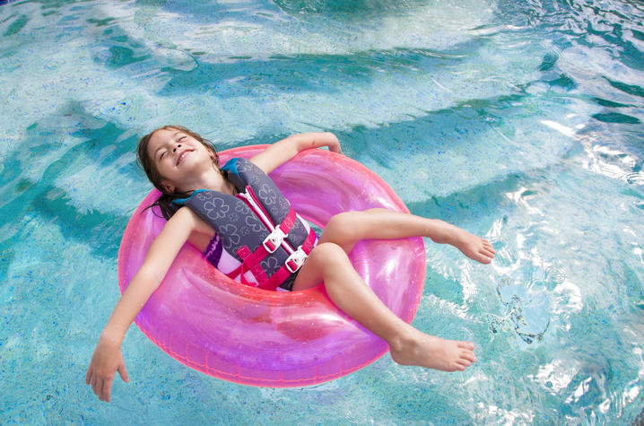 little girl in pink tube floating in pool