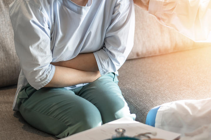 girl on couch clutching stomach