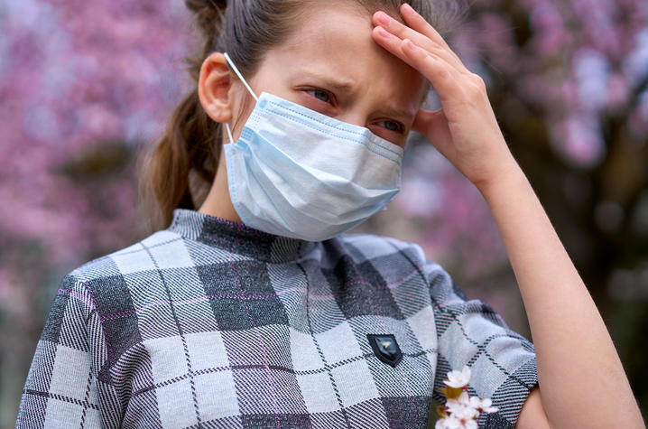 stock photo of masked young female with hand on her forehead