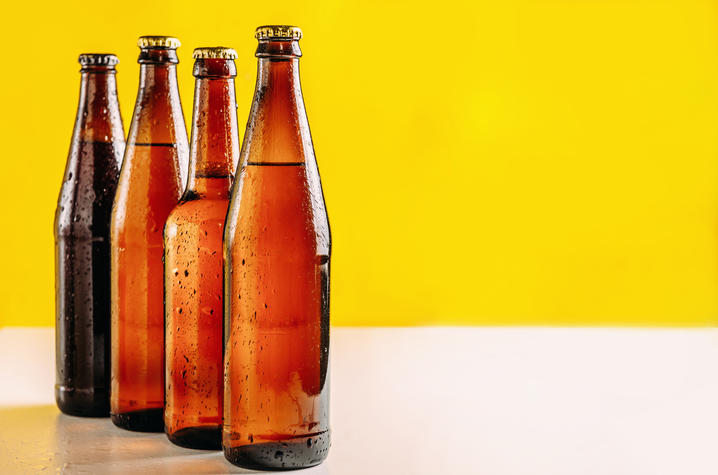 Photo of bottles Four beer bottles lined up against a yellow background.