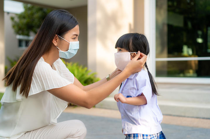 Photo of mother adjusting child's face mask