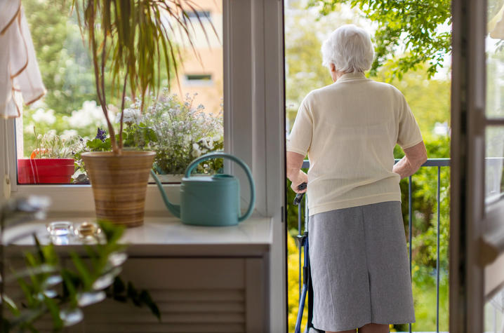 Woman with walker looks over balcony.